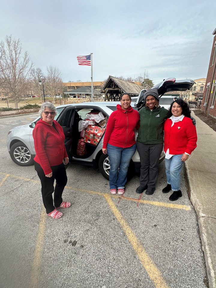 Volunteers and a family loading presents into a car.
