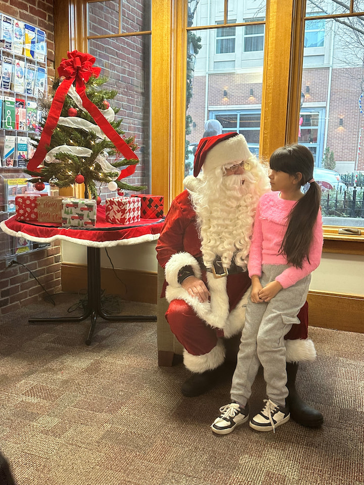 A girl sitting with Santa.