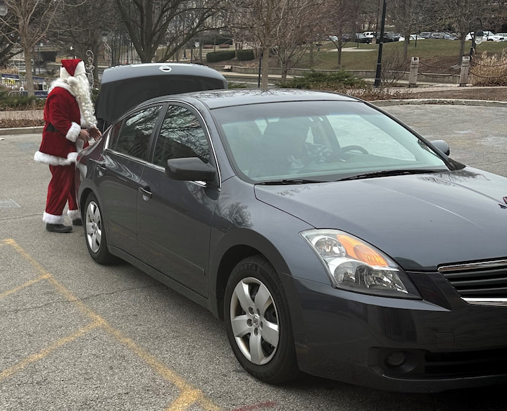 Santa getting presents out of a car.