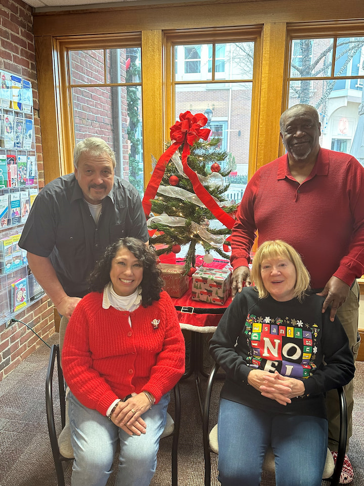 Four volunteers posing by the Christmas tree.